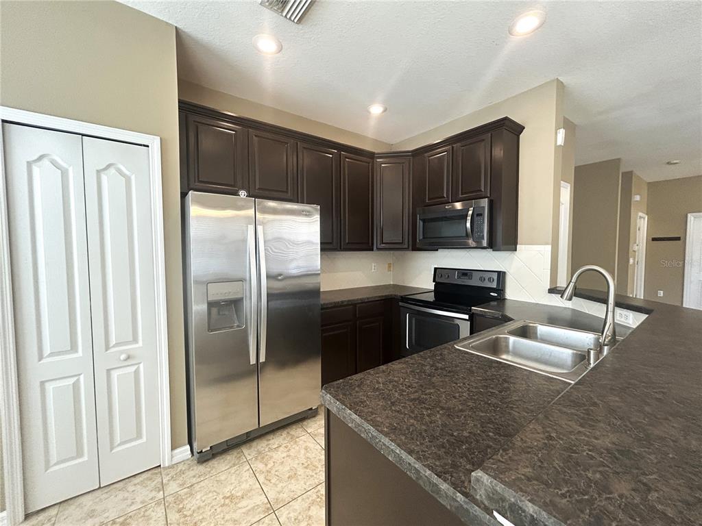 9036 Moonlit Meadows Loop Riverview, FL 33578 - Photo 10 of 20 a kitchen with stainless steel appliances granite countertop a refrigerator and a sink