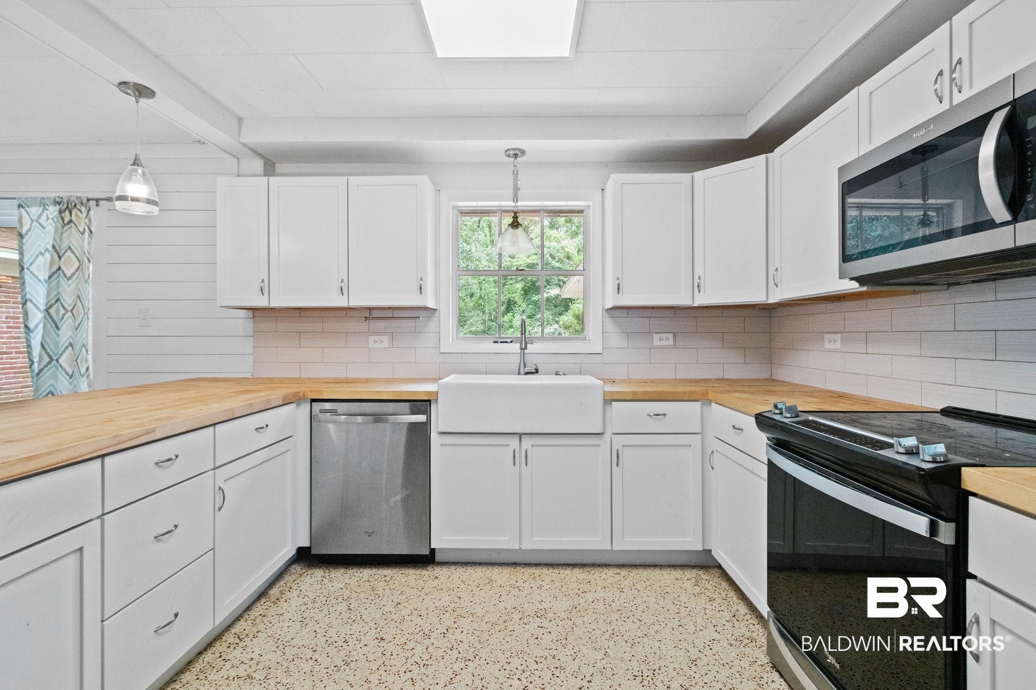 384 Old Bratt Road Atmore, AL 36502 - Photo 15 of 64 U-shaped kitchen featuring white cabinetry, light wood-finish countertops, stainless steel appliances, and a white farmhouse sink