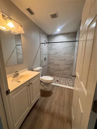 an empty room with wooden floor ceiling fan and windows