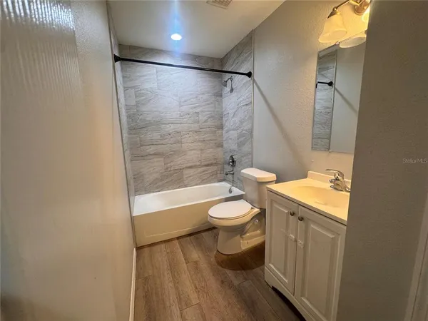 an empty room with wooden floor ceiling fan and windows