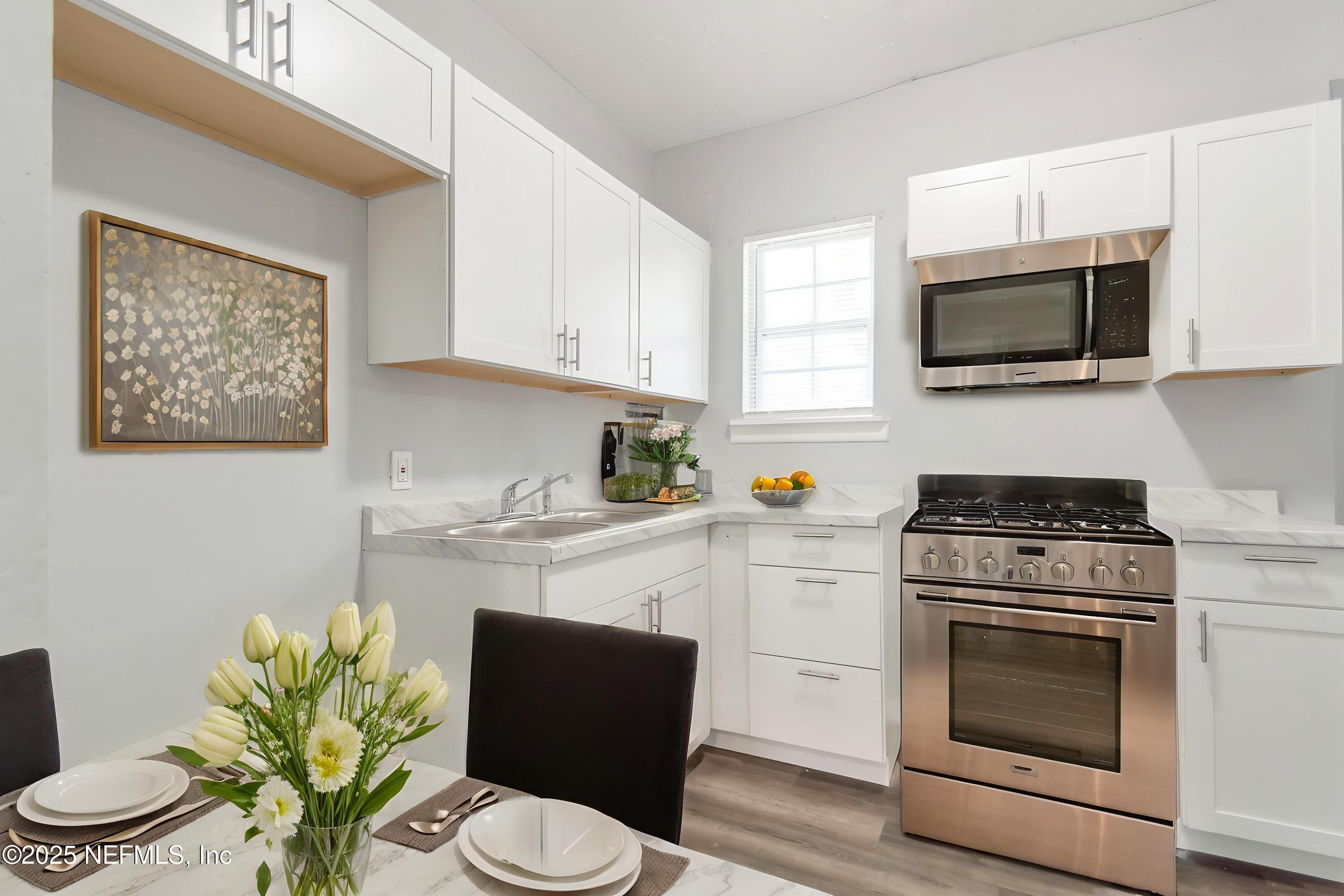 1165 Hart Street Jacksonville, FL 32209 - Photo 7 of 22 a kitchen with stainless steel appliances a stove a microwave sink cabinets and a wooden floor