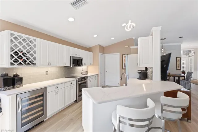 a large white kitchen with a stove a sink dishwasher and a refrigerator with wooden floor