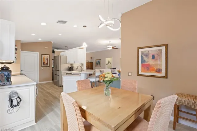 a living room with stainless steel appliances furniture a dining table and kitchen view