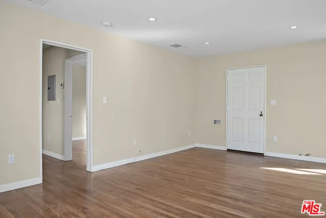 a view of an empty room with wooden floor and closet