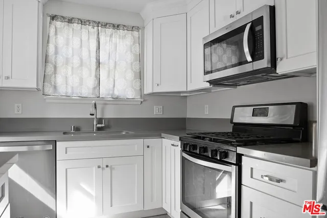 a kitchen with granite countertop white cabinets stainless steel appliances and a sink