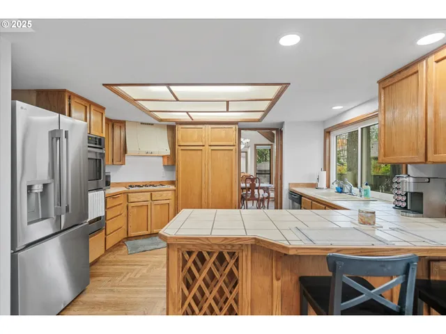 a kitchen with stainless steel appliances kitchen island granite countertop a refrigerator a sink dishwasher with a dining table and chairs