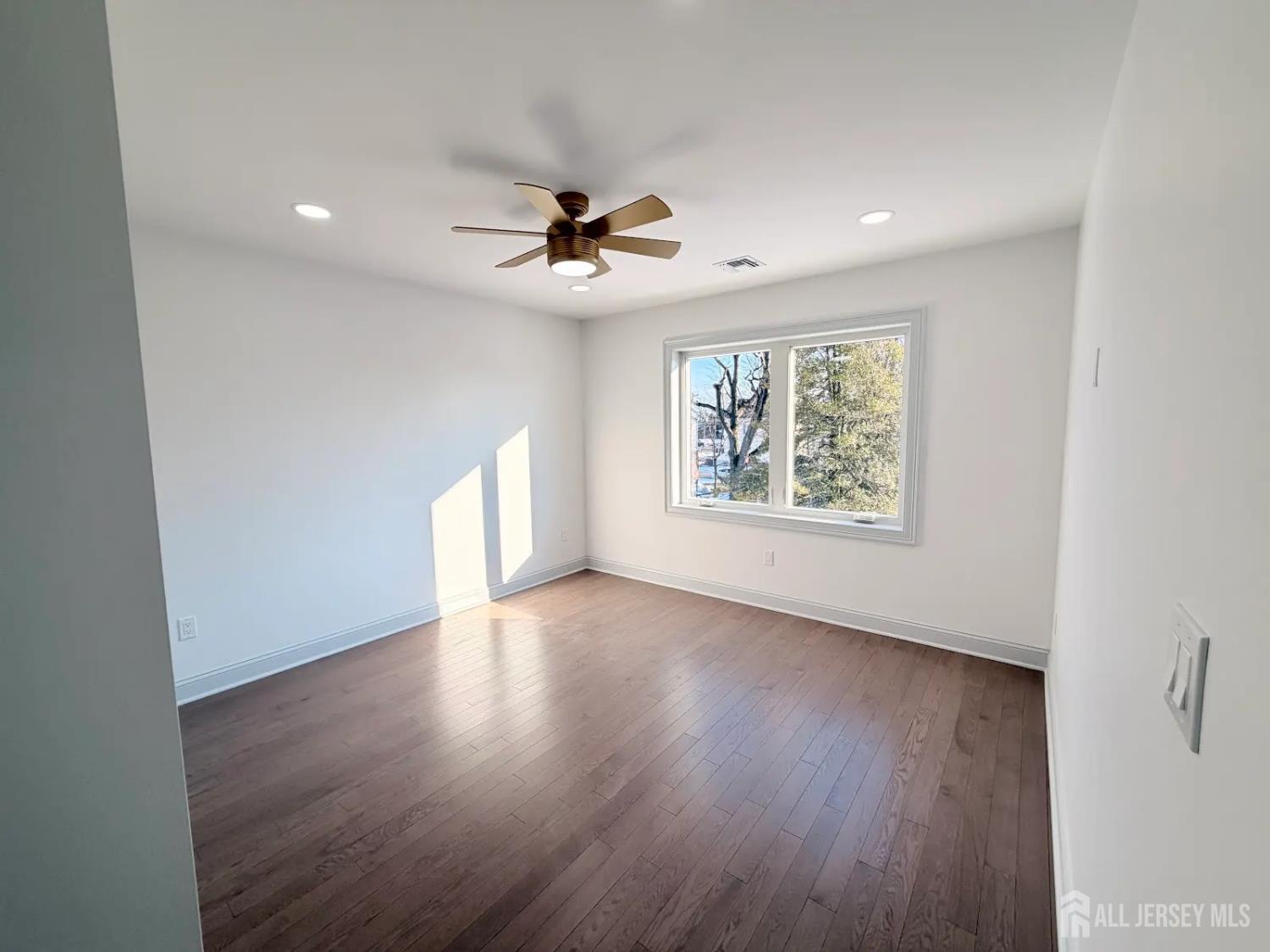 46 Foyer Street Edison, NJ 08817 - Photo 8 of 12 an empty room with wooden floor ceiling fan and windows