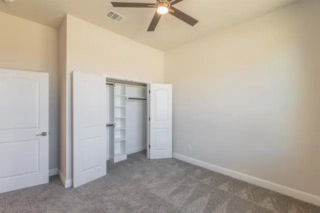 an empty room with closet and a ceiling fan