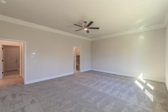 an empty room with a ceiling fan and carpet