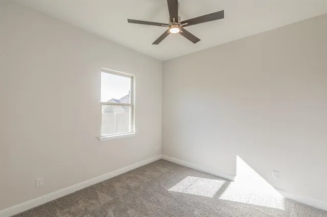 an empty room with a window and a fan