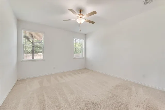 an empty room with windows and chandelier fan