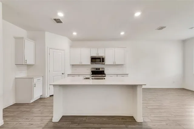 a large kitchen with stainless steel appliances granite countertop a stove a sink and white cabinets