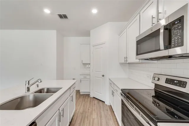 a kitchen with stainless steel appliances a stove a sink and microwave