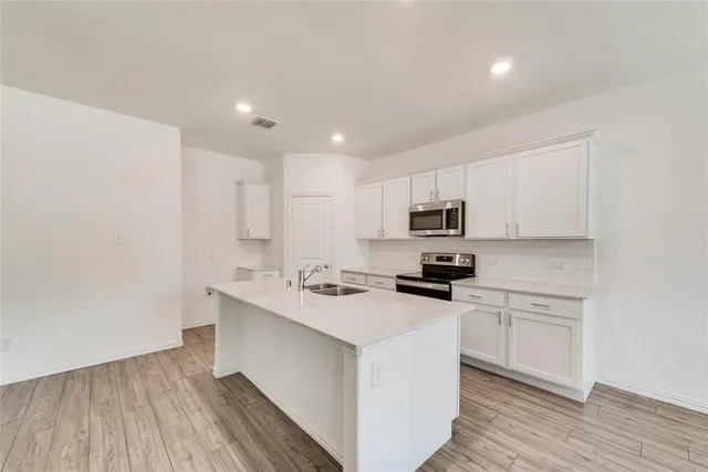 a kitchen with a sink white cabinets and stainless steel appliances