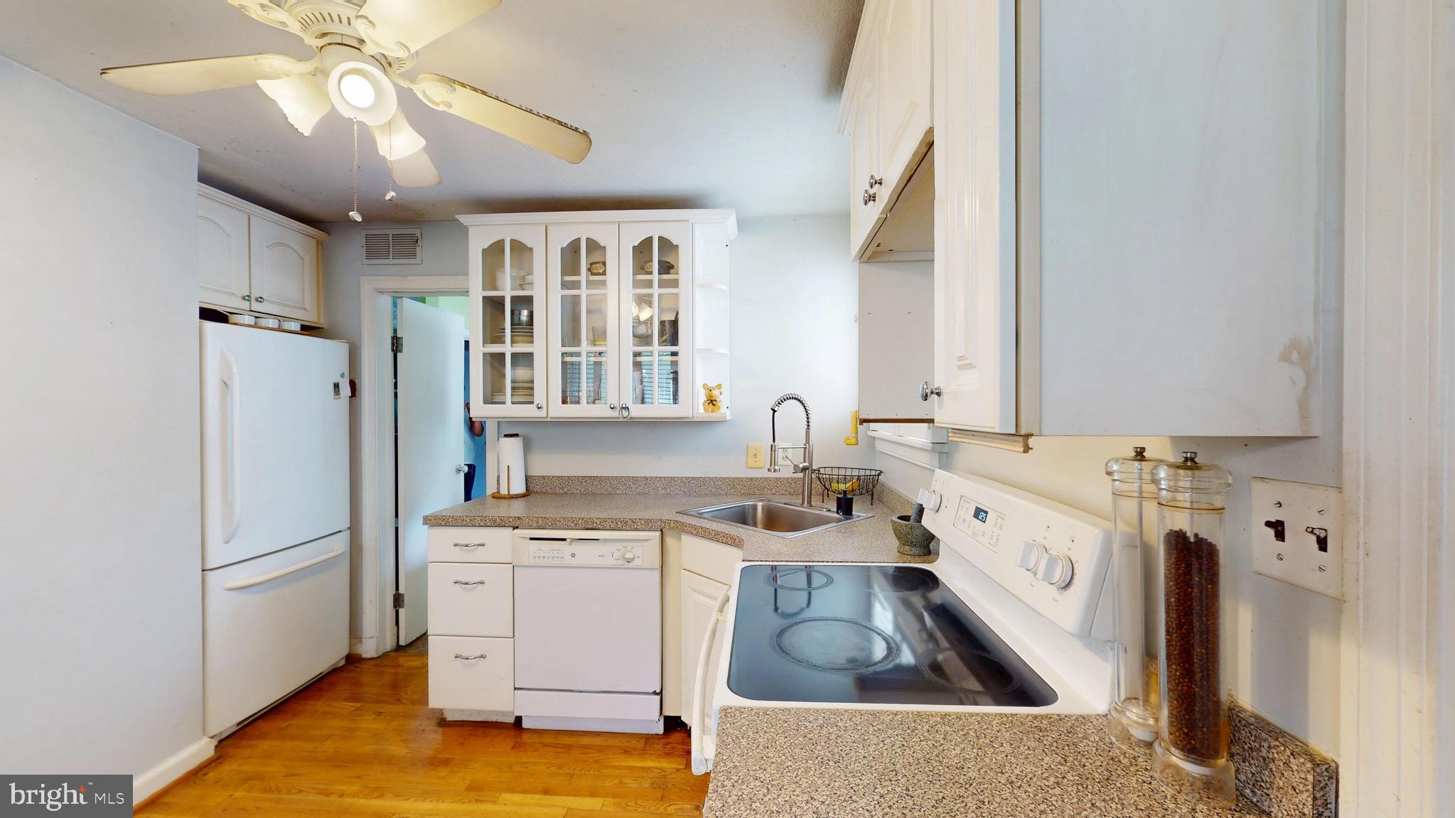 6103 Manor Road Clinton, MD 20735 - Photo 19 of 48 a kitchen with a refrigerator a sink dishwasher a stove and a dining table with wooden cabinet
