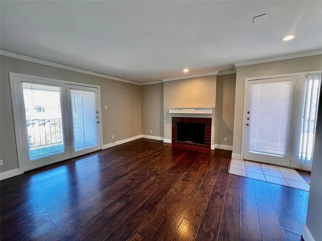 an empty room with wooden floor fireplace and windows