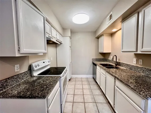 a kitchen with granite countertop a sink and a stove