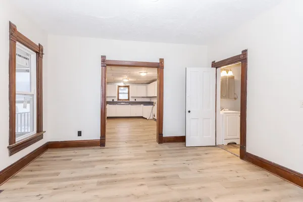 a view of an empty room with window and wooden floor