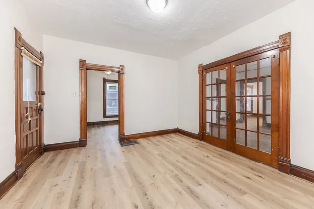 a view of an empty room with wooden floor and a window