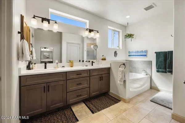 a spacious bathroom with a double vanity sink a mirror and a bathtub