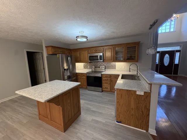 a kitchen with stainless steel appliances granite countertop a stove top oven a refrigerator a sink and dishwasher with wooden floor