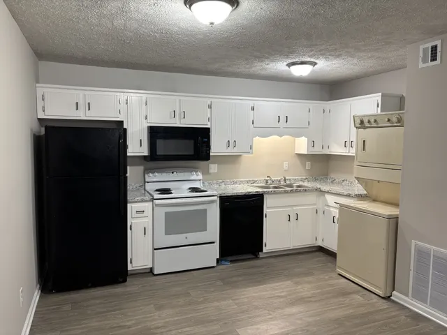a kitchen with granite countertop white cabinets and stainless steel appliances