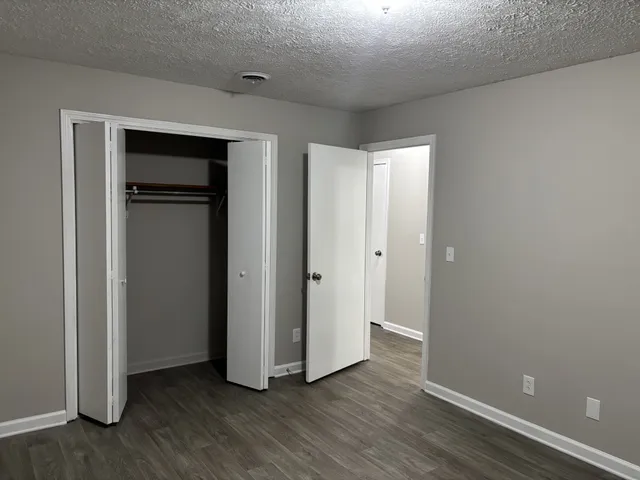 a view of an empty room with closet and a window