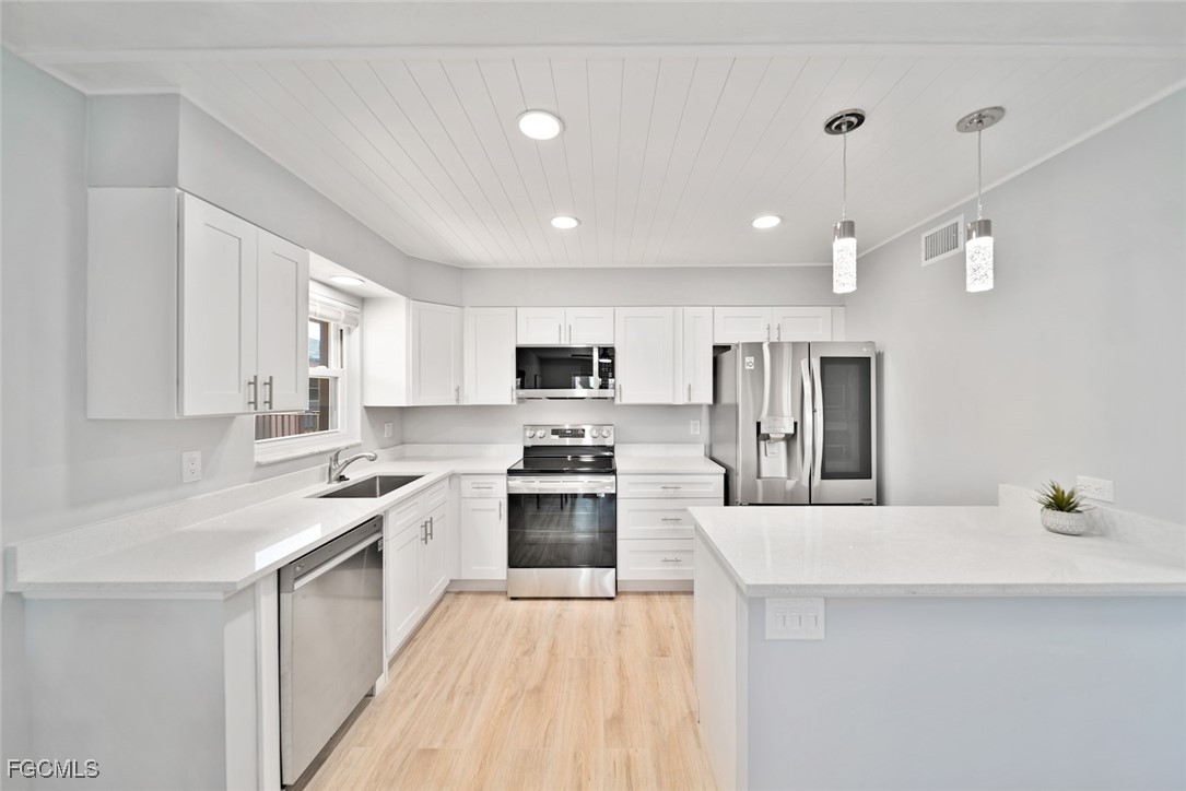 16881 Davis Road, Unit 721 Fort Myers, FL 33908 - Photo 7 of 23 a large kitchen with stainless steel appliances kitchen island a sink dishwasher a stove and a refrigerator with wooden floor