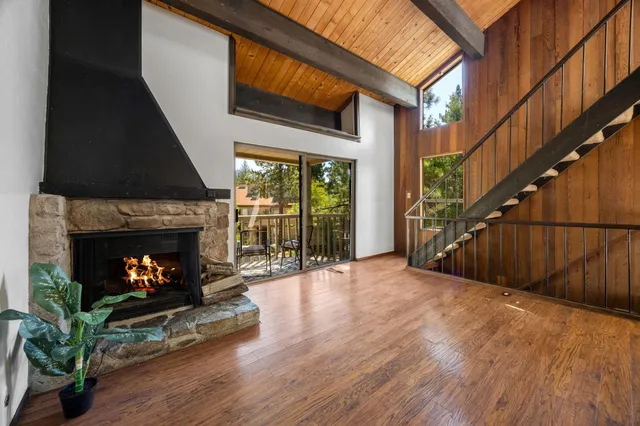 a view of an empty room with wooden floor fireplace and a window