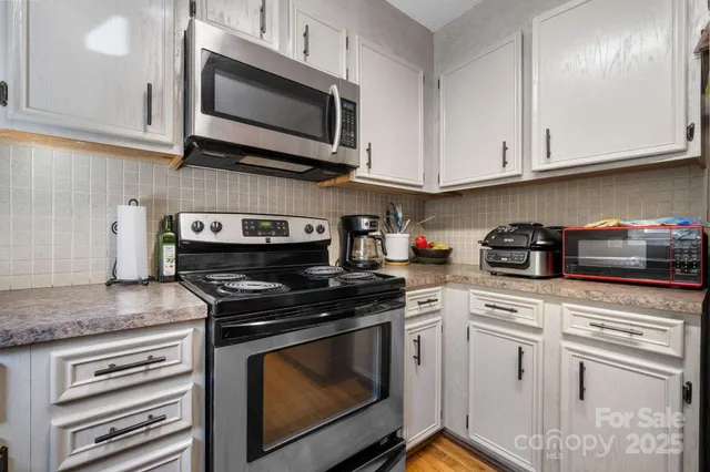 a kitchen with stainless steel appliances granite countertop grey cabinets a stove a sink and dishwasher