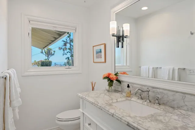 a bathroom with a granite countertop toilet a sink and mirror