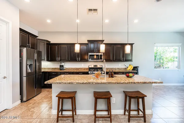 a kitchen with granite countertop kitchen island stainless steel appliances a stove sink microwave and cabinets