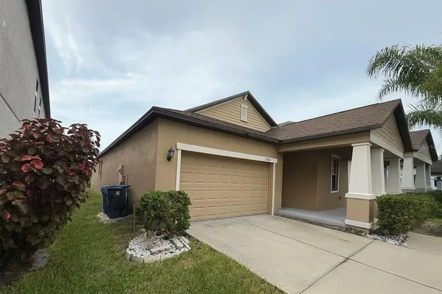 a view of a house with a small yard plants and a large tree