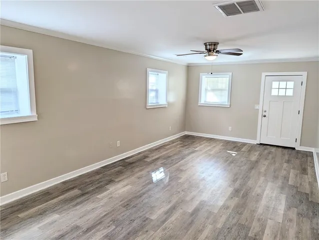 a view of an empty room with wooden floor and a window