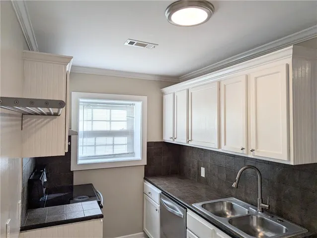 a kitchen with granite countertop a sink stainless steel appliances white cabinets and a window