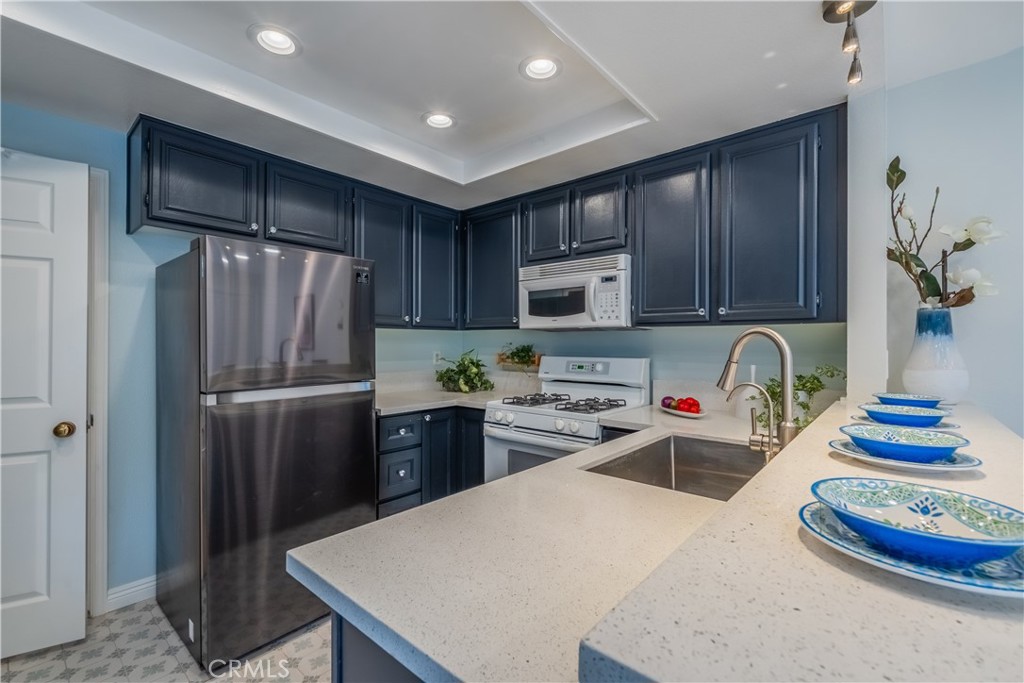 19 Dartmouth Irvine, CA 92612 - Photo 10 of 44 a kitchen with stainless steel appliances granite countertop a refrigerator a stove a sink dishwasher and wooden cabinets with wooden floor