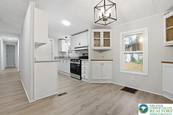 a kitchen with stainless steel appliances granite countertop a refrigerator a stove a sink dishwasher and white cabinets with wooden floor