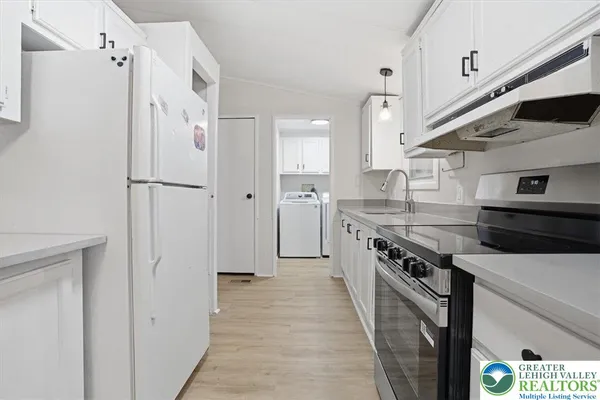 a kitchen with stainless steel appliances a refrigerator a stove and white cabinets