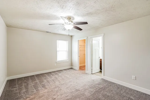 an empty room with windows and fan