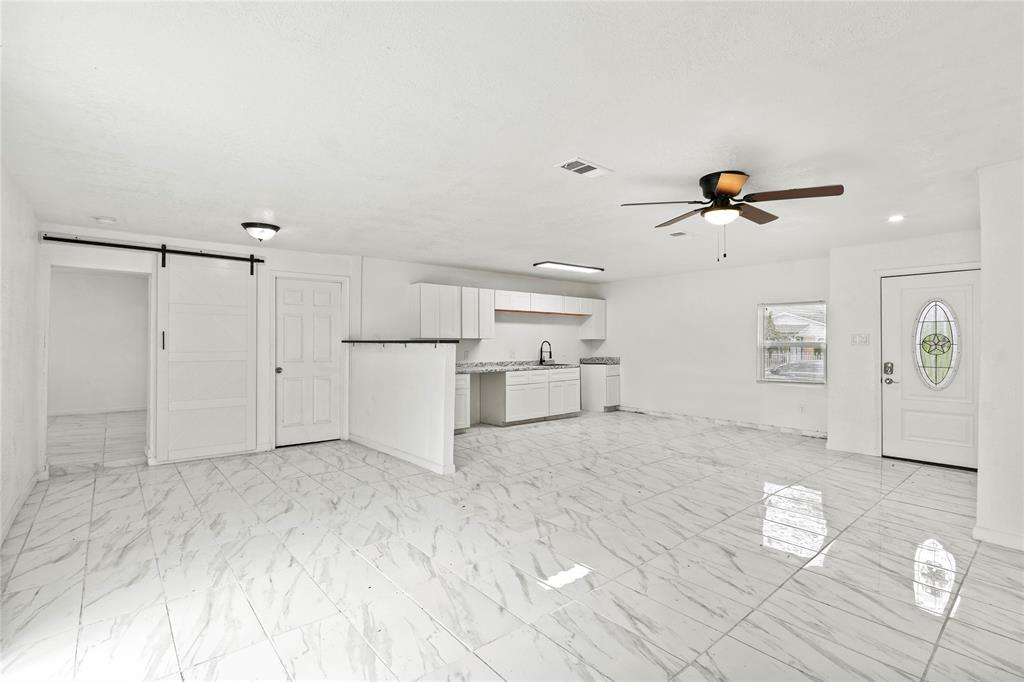 Unfurnished living room with a barn door, ceiling fan, and sink