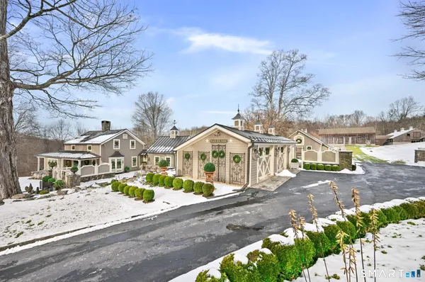 a front view of a house with a yard covered with snow and trees