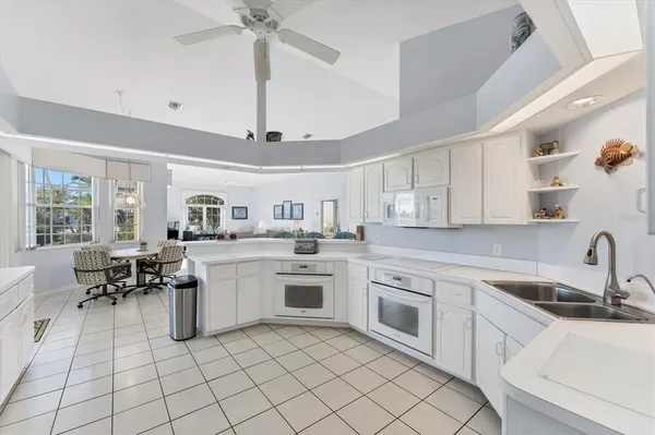 a kitchen with white cabinets appliances and a window