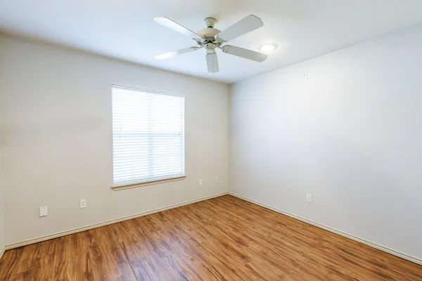 an empty room with a window and a ceiling fan