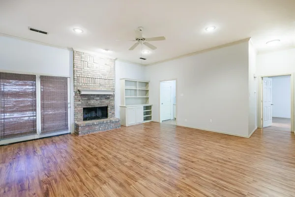 an empty room with wooden floor fireplace and windows