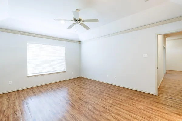 an empty room with wooden floor fan and windows