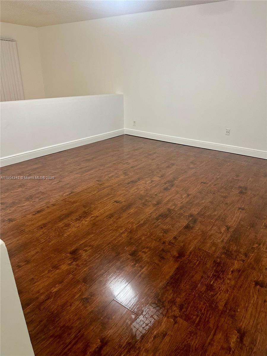 18007 Northwest 68th Avenue, Unit U103 Hialeah, FL 33015 - Photo 5 of 9 a view of an empty room with wooden floor