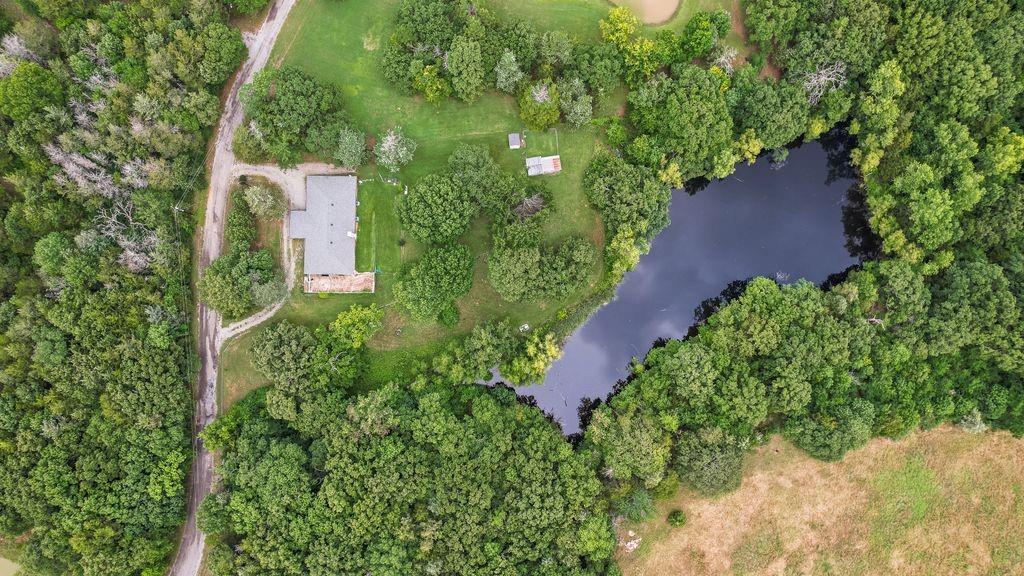 298 Butterfield Road Denison, TX 75021 - Photo 2 of 34 Expansive lot featuring a private pond, mature tree coverage, a main residence with a gray roof, and a gravel drive