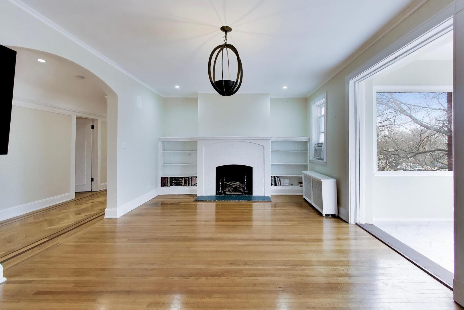 825 East Drexel Square, Unit 2 Chicago, IL 60615 - Photo 7 of 25 an empty room with wooden floor fireplace and windows