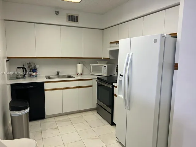 a kitchen with a refrigerator sink and cabinets