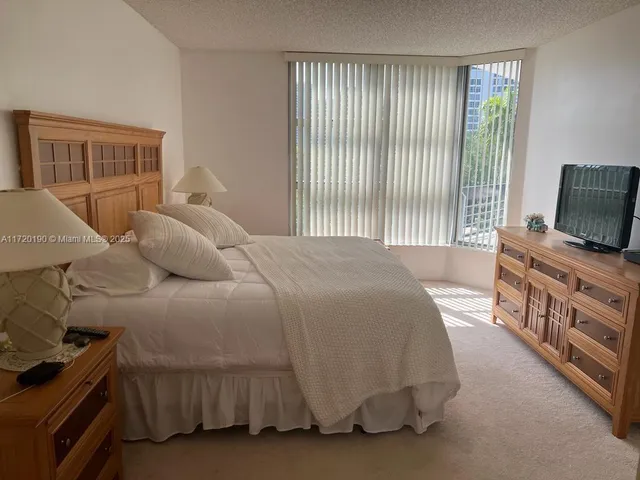 a bedroom with a bed and a flat tv screen on dresser